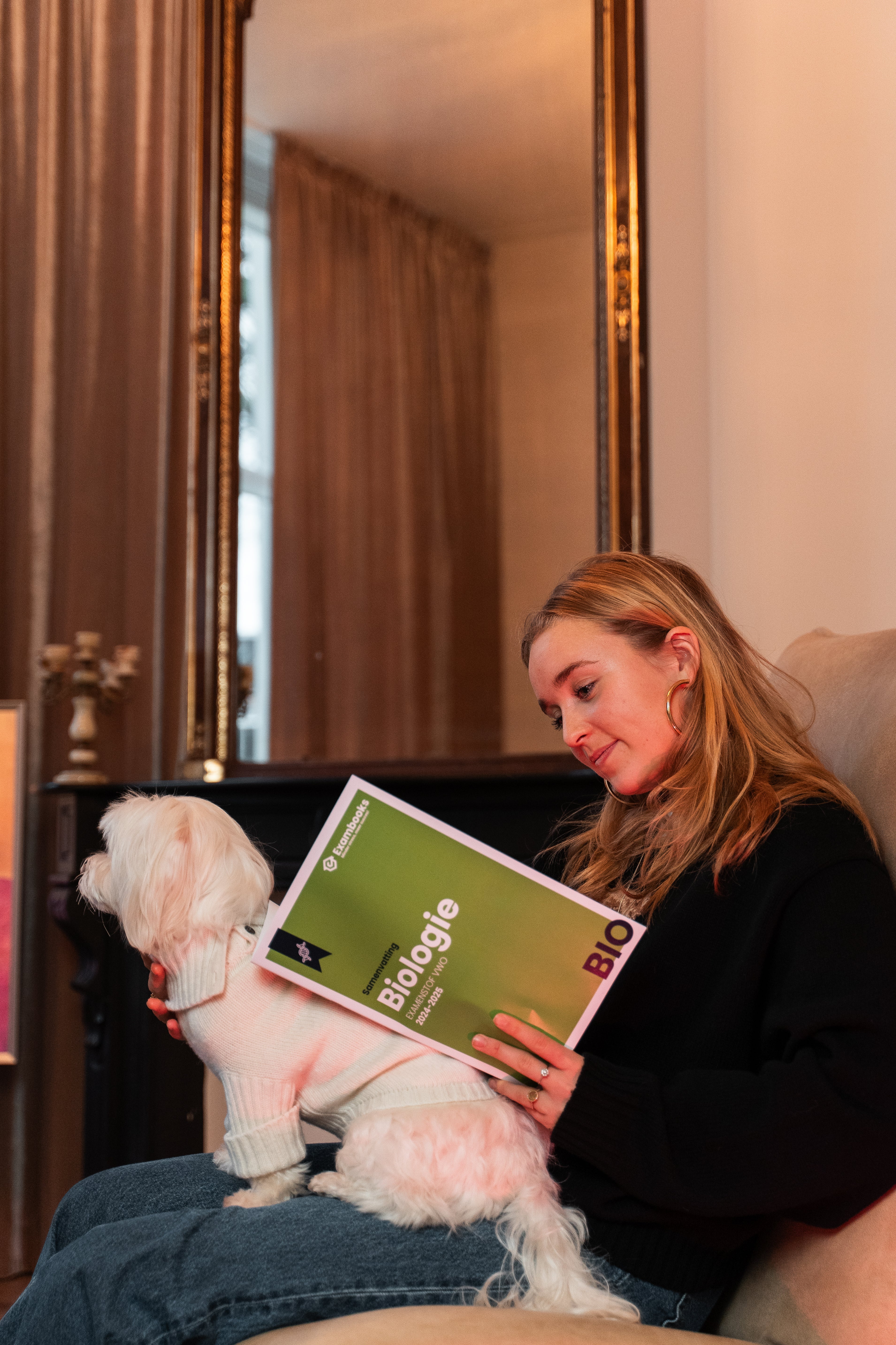 Student studeert biologie met een ExamBooks-studieboek op schoot, terwijl haar hondje gezellig bij haar zit tijdens de examenvoorbereiding.